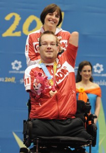 November 16 2011 - Guadalajara, Mexico: Josh Vandervies waves to his Canadian fans with his assistant Dalia Mykolaiteine behind him after receiving his Bronze Medal in Boccia BC4 in the Multipurpose Gymnasium Revolución at the 2011 Parapan American Games in Guadalajara, Mexico. Photo: Matthew Murnaghan/Canadian Paralympic Committee